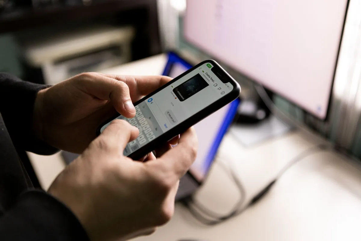 Pessoa digitando no celular com balões de conversa na tela - vendas pelo WhatsApp automatizadas com agentes de IA da Poupar AI
